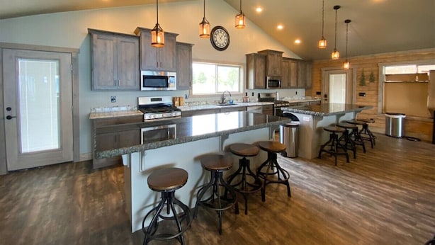 A spacious kitchen with a large island, bar stools, and pendant lighting.