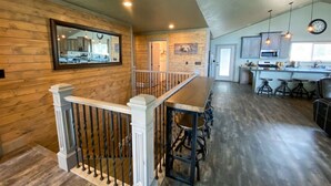 A spacious kitchen with a long counter, bar stools, and pendant lighting.