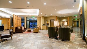 A spacious lobby with a reception desk, seating area, and a large window offering a view of the cityscape.