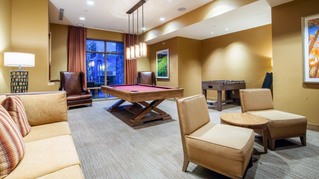 Une pièce équipée d’une table de billard, de sièges confortables et d’une table de baby-foot.