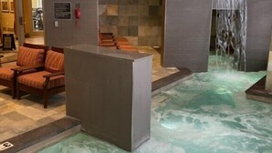 A spa area with a hot tub, seating, and a waterfall feature.