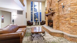 Una sala de estar con chimenea de piedra, sofá de cuero y una mesa de centro.
