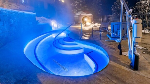 A heated outdoor pool with a spiral design, surrounded by a stone wall and metal railings. - Marriotts Streamside at Vail - 1 Bedroom (Vail)