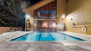 A swimming pool with a wooden deck and a building with large windows in the background. - Marriotts Streamside at Vail - 1 Bedroom (Vail)