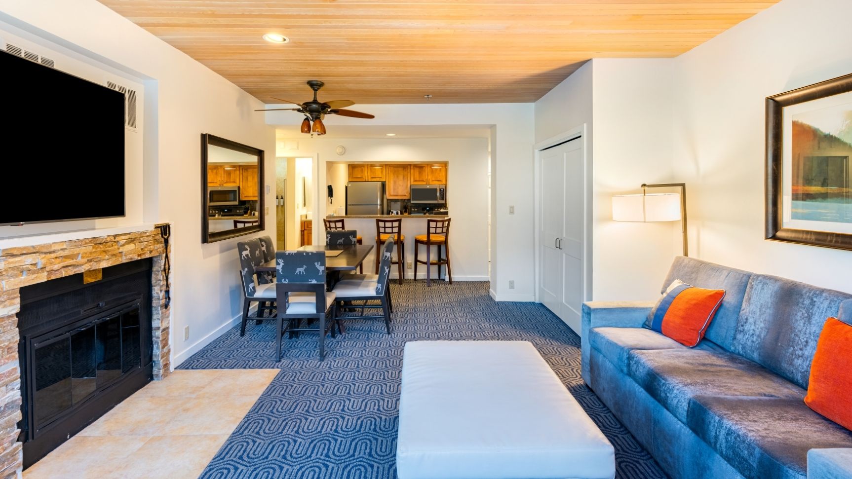 A modern living room with a fireplace, a dining area, and a kitchen in the background.