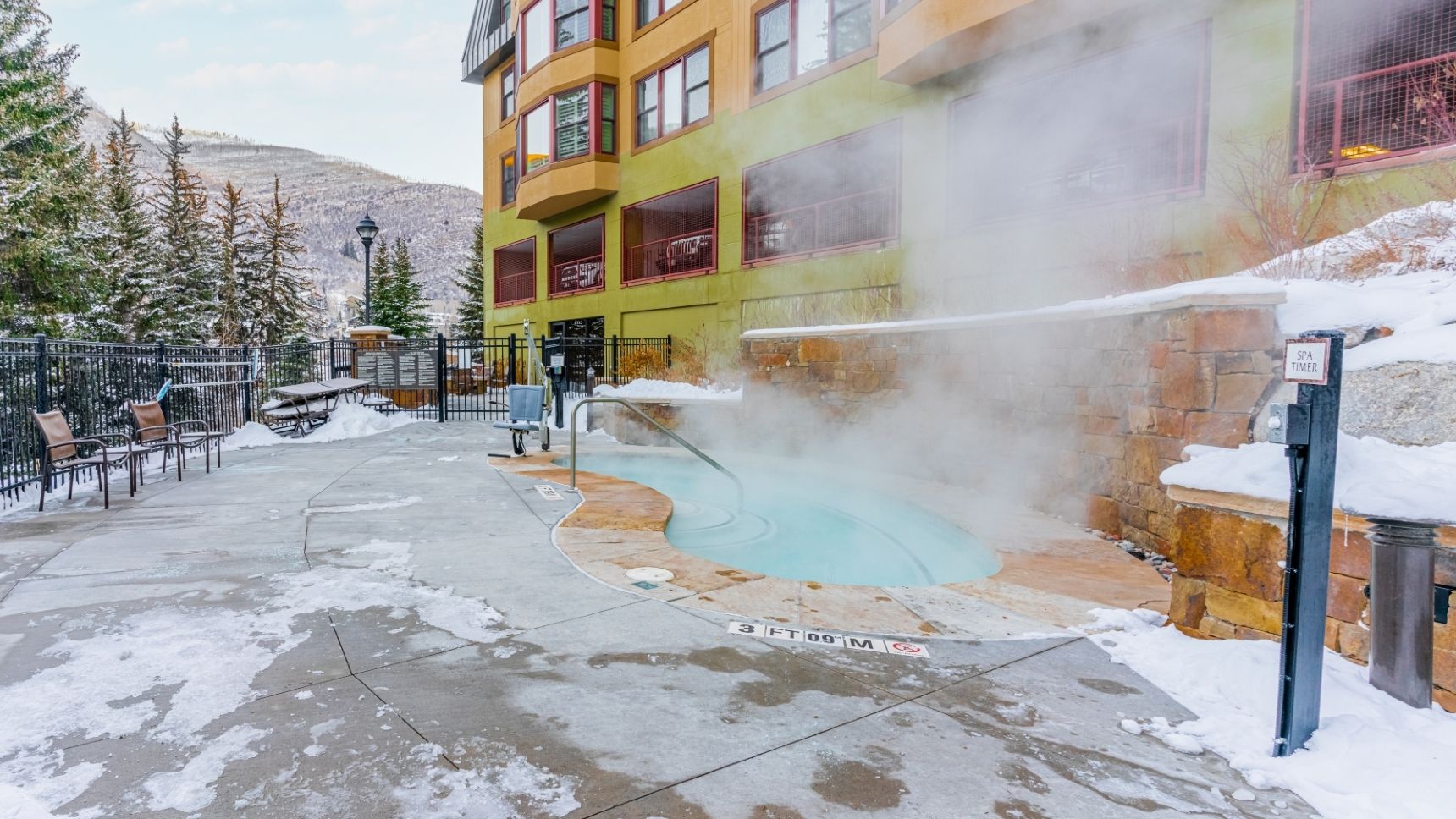 A spa area with a hot spring, outdoor seating, and a building with multiple windows.