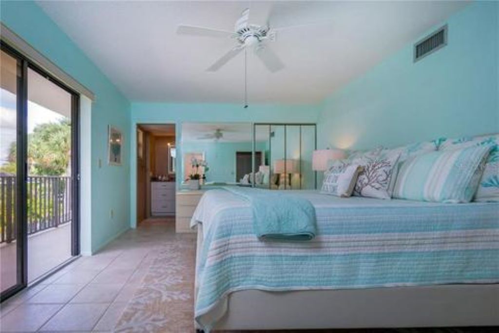 Une chambre avec un lit, un ventilateur de plafond, un balcon et une vue sur l’extérieur.