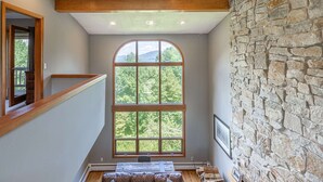 A room with a large arched window, stone wall, wooden beam ceiling, and a ceiling fan. - Only 5 minutes away from Stratton Mountain  (Winhall)
