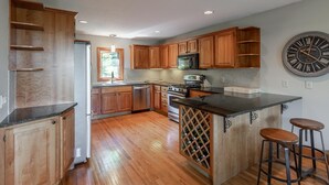 A kitchen with wooden cabinets, a stainless steel refrigerator, a microwave, a stove, and a wine rack. - Only 5 minutes away from Stratton Mountain  (Winhall)