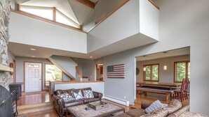 A spacious living room with a stone fireplace, leather sofas, a wooden coffee table, and a large American flag on the wall. - Only 5 minutes away from Stratton Mountain  (Winhall)