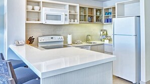 Una cocina moderna con armarios blancos, microondas, estufa, refrigerador y una isla grande.