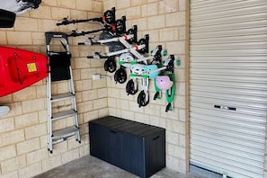 Un garage avec un mur en briques, une porte à volet roulant fermée et une échelle en métal.