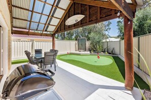 A covered patio with a grill, a dining table, and chairs.