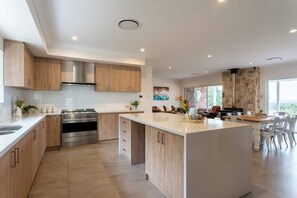 A modern kitchen with a central island, stainless steel appliances, and a dining area with a view.