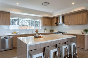 Una cocina moderna con una isla grande, armarios de madera y un lavavajillas.
