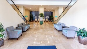 Un vestíbulo con un área de estar central, una escalera y un letrero que dice 'EMERALD BEACH'.