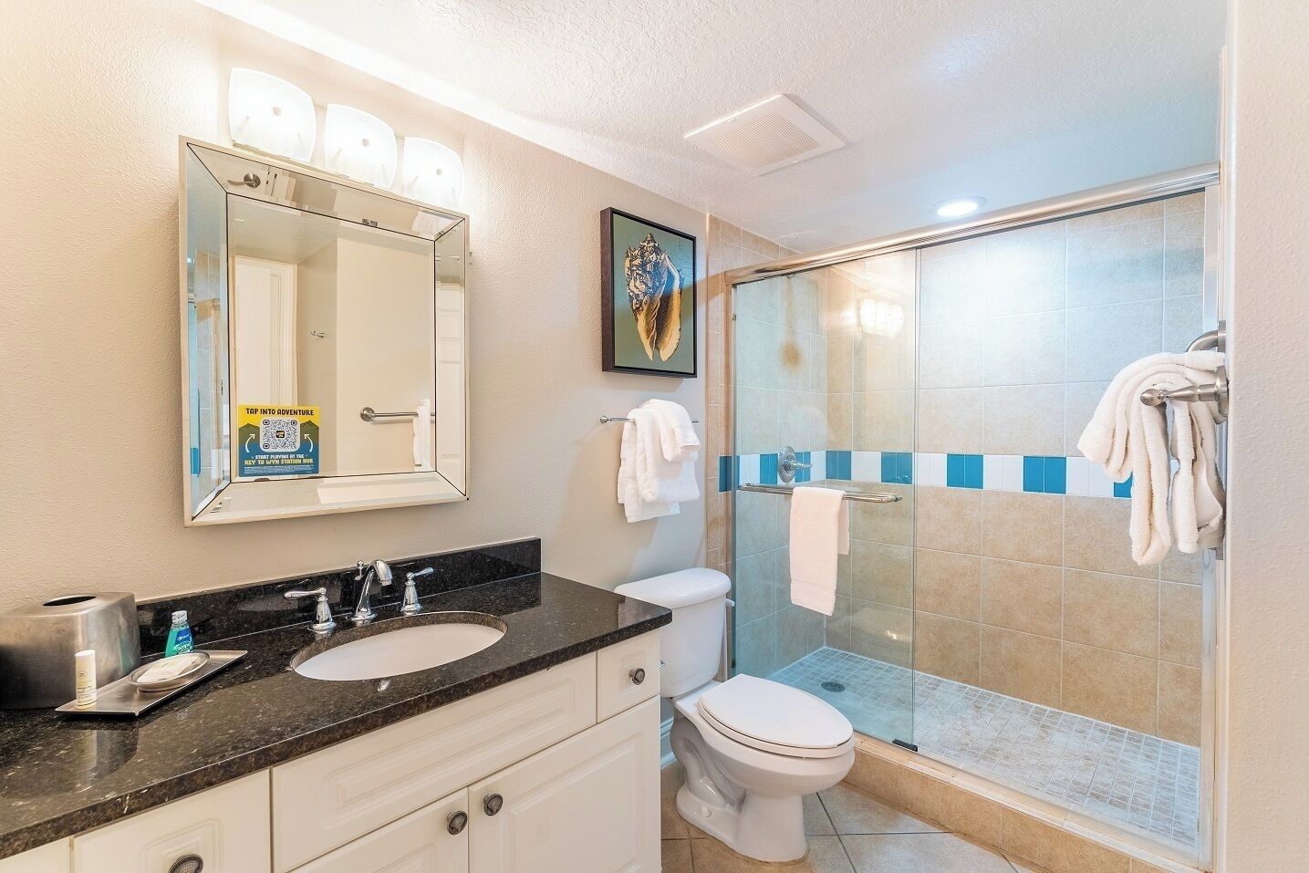 A bathroom with a glass-enclosed shower, a sink with a mirror, and a toilet.