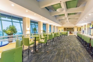 A spacious indoor area with multiple seating arrangements, large windows, and a view of the outside.