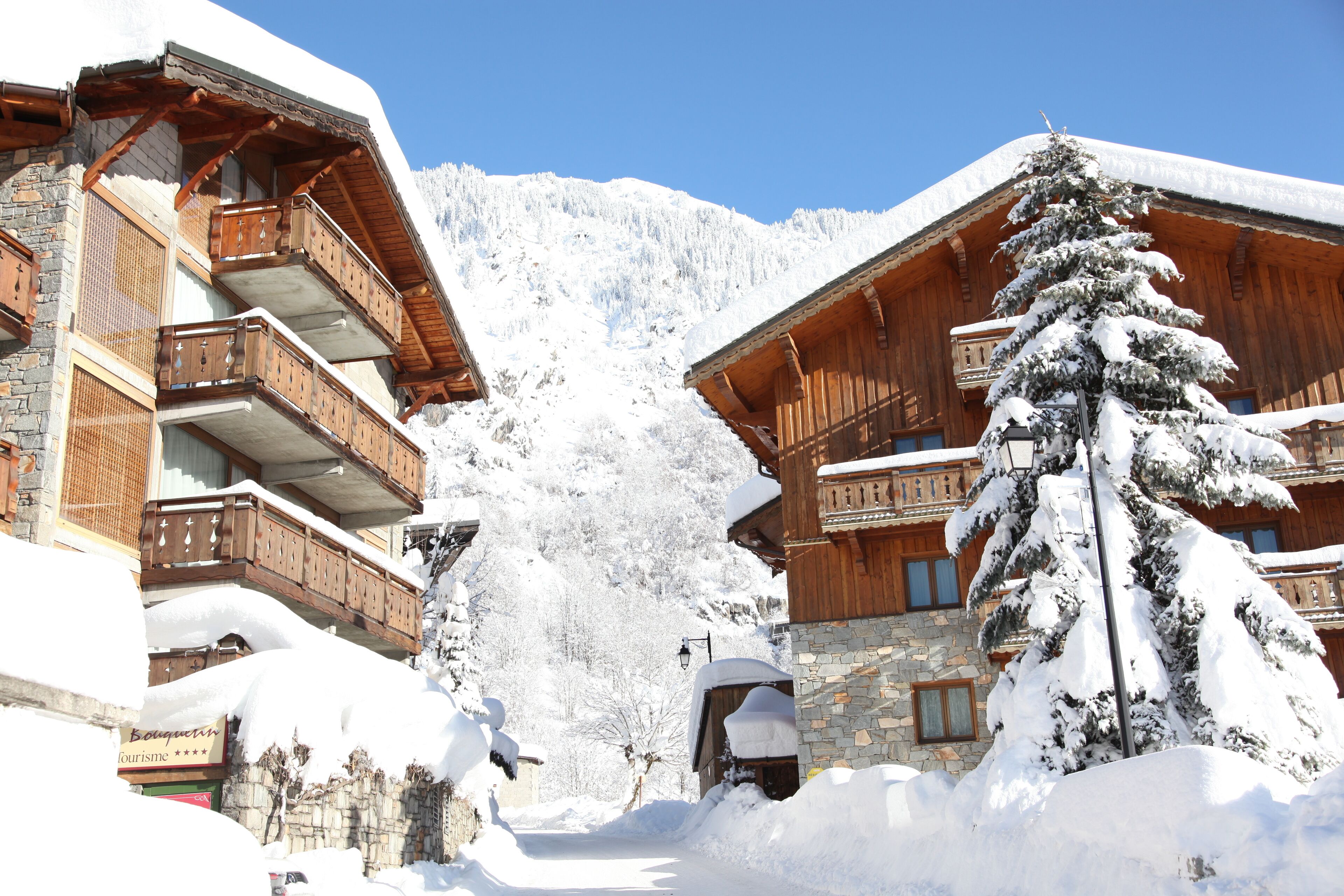 Ein mit Schnee bedecktes Berghotel mit Holzbalkonen und einer Steinfassade.