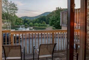Enjoy a serene river view from this deck, featuring two comfortable chairs and a natural backdrop.