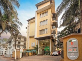 Un hotel de varios pisos con una entrada destacada, palmeras y un cartel de Trevon Hotels & Resorts.