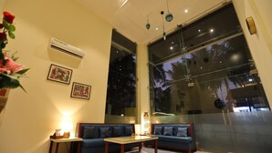 Una sala moderna con un sofá, una mesa de centro y un ventanal con vista a palmeras.