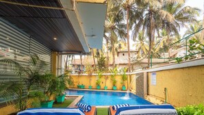 Zona junto a la piscina con sillas de descanso, una piscina y plantas en macetas.