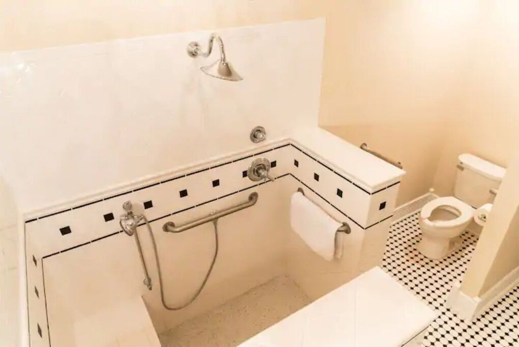 A bathroom with a shower, toilet, and a towel rack.