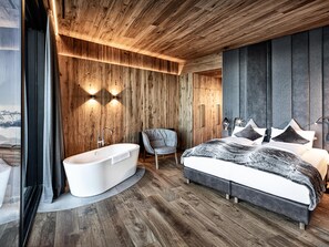 Relax in this serene bedroom with a large bed, bathtub, and cozy seating area.