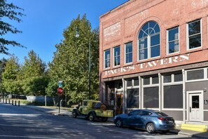 A brick building with a sign reading 'Pack's Tavern' and a vintage car parked in front.