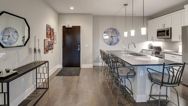 A modern kitchen with a central island, pendant lighting, and a dining area with bar stools.