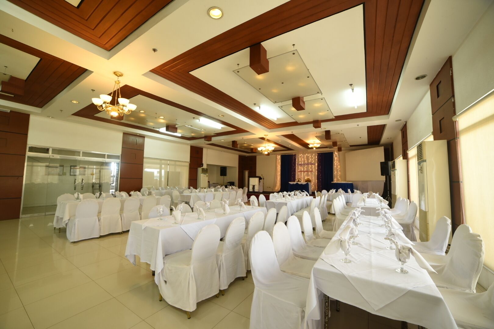 A banquet hall with rows of tables set for dining, equipped with chairs and table settings.