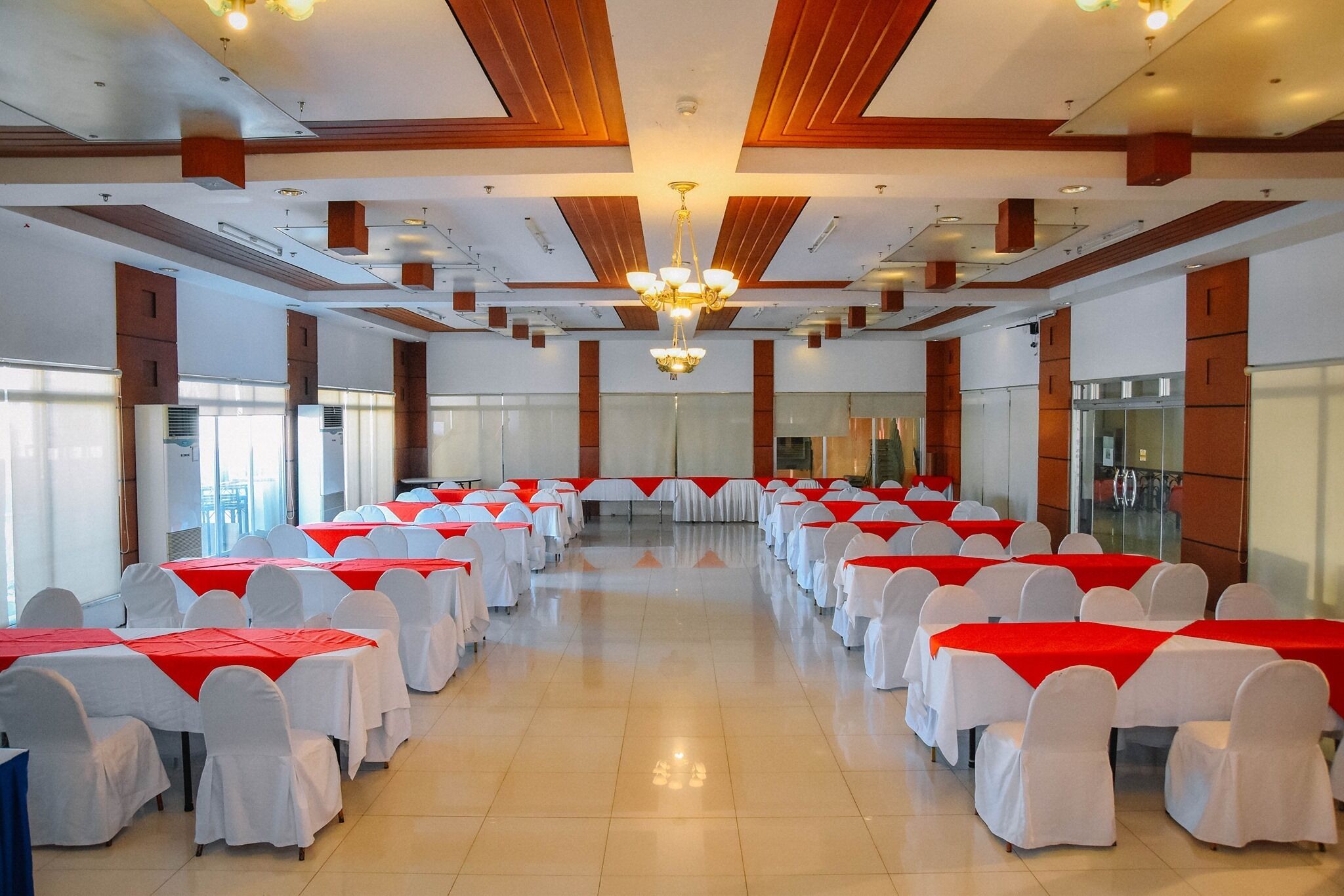 A conference room with rows of tables and chairs, large windows, and a chandelier.