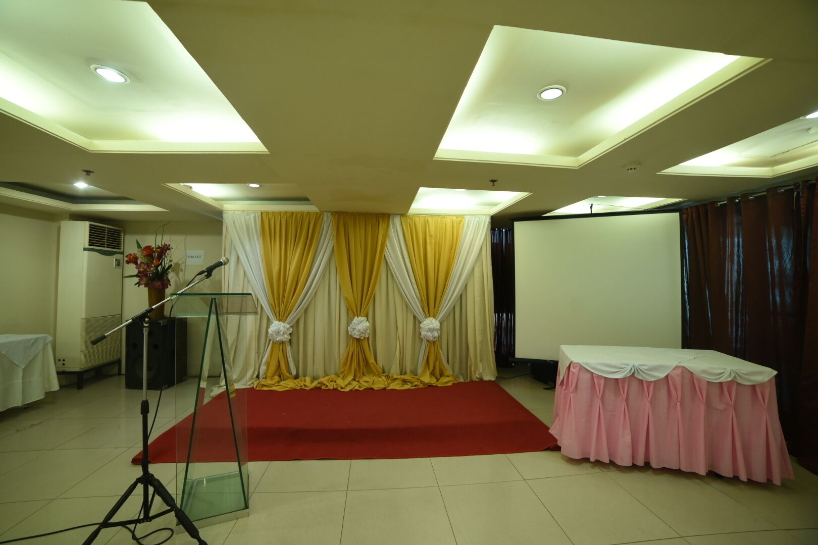A conference room with a stage, a podium, and a projector screen.