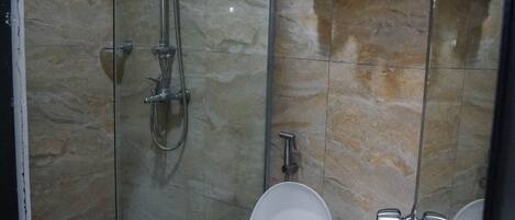 A modern bathroom with a glass-enclosed shower, a toilet, and a towel rack.
