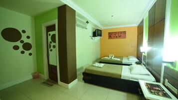 A hotel room with two beds, a television on the wall, and a small table with a magazine.