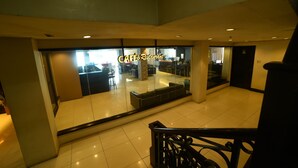 A modern hotel lobby with a glass partition, a staircase, and a reception area. - Marcian Business Hotel (Zamboanga)