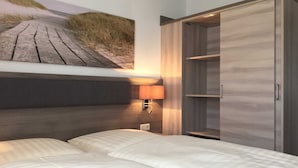 Camera da letto con un letto, una testiera, un armadio, una lampada a parete e un quadro a tema spiaggia.