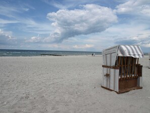 Une plage avec une seule chaise longue et un auvent rayé.
