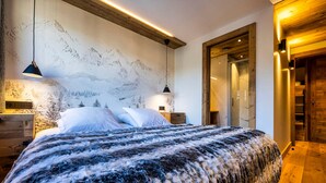 Une chambre moderne avec un grand lit, une tête de lit en bois et une fresque murale représentant des montagnes.