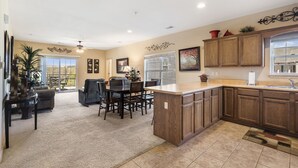 A spacious kitchen with wooden cabinets, a large island, and a dining area with a table and chairs. - Walk-In 3 BD/3BA Condo -Covered Deck with Pool View, Golf/Ticket Discounts, Resort Perks (Branson)
