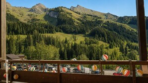 A mountain view from a wooden balcony with a red table, surrounded by colorful paper lanterns. - Bright apartment, near slopes, pets allowed (La Clusaz)