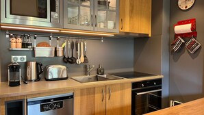 A modern kitchen with stainless steel appliances, wooden cabinets, and a built-in oven. - Bright apartment, near slopes, pets allowed (La Clusaz)
