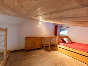 Una habitación pequeña con una litera, un escritorio y una silla.