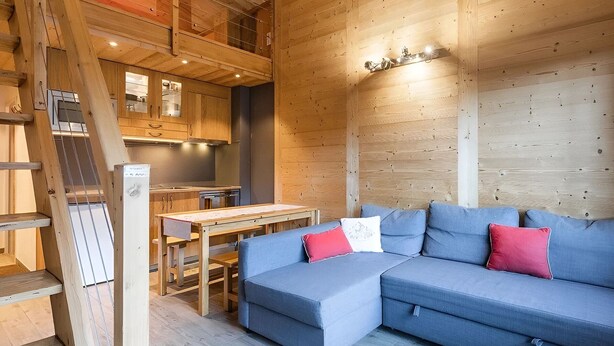 A modern cabin interior with a wooden interior, a dining area, and a sofa. - Bright apartment, near slopes, pets allowed (La Clusaz)