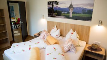 Ein ordentlich bezogenes Bett mit floralem Bettzeug, einem Holzkopfende und einem Nachttisch mit Lampe.