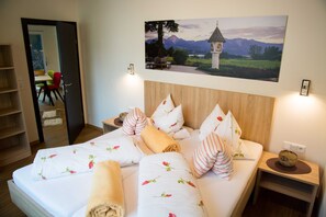 Un lit bien fait, avec une literie à motifs floraux, une tête de lit en bois et une table de chevet avec une lampe.