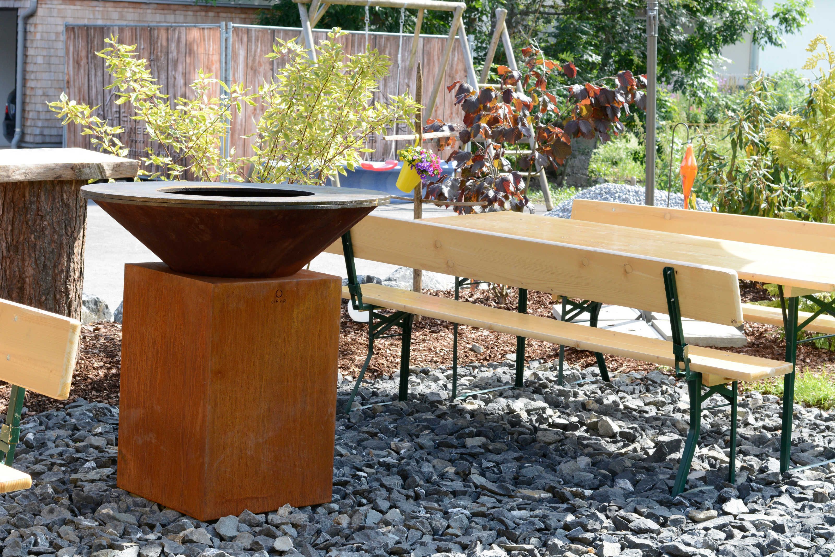 An outdoor seating area with benches and a central planter.