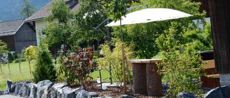 A residential area with a stone wall, a wooden bench, and a white umbrella.