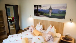 Ein ordentlich bezogenes Bett mit floralem Bettzeug, einem Holzkopfende und einem Nachttisch mit Lampe.